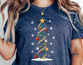 May include: Navy blue t-shirt featuring a DNA strand designed as a Christmas tree. The tree is decorated with red and yellow ornaments, a gold star, and snowflakes. The shirt is a casual, festive apparel item.