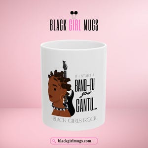 May include: White ceramic mug with a black and white illustration of a woman with a guitar. The text on the mug reads "If I start a band-tu you cantu... Black girls rock".