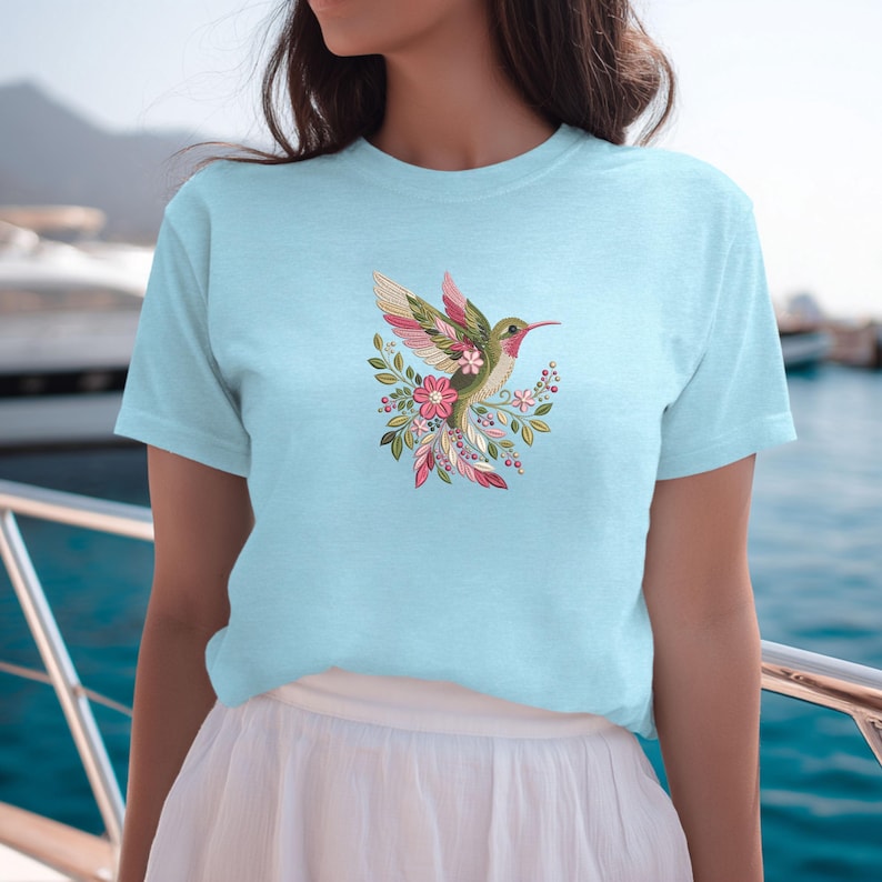 Floral hummingbird machine embroidery design with pink flowers, green leaves, cream feathers and botanical branches.