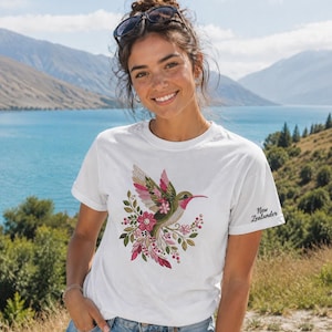 Floral hummingbird machine embroidery design with pink flowers, green leaves, cream feathers and botanical branches.