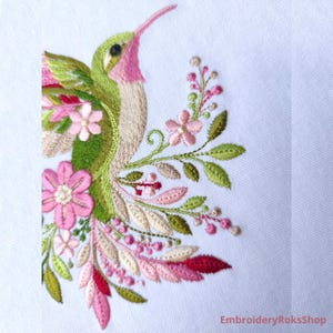 Floral hummingbird machine embroidery design with pink flowers, green leaves, cream feathers and botanical branches.