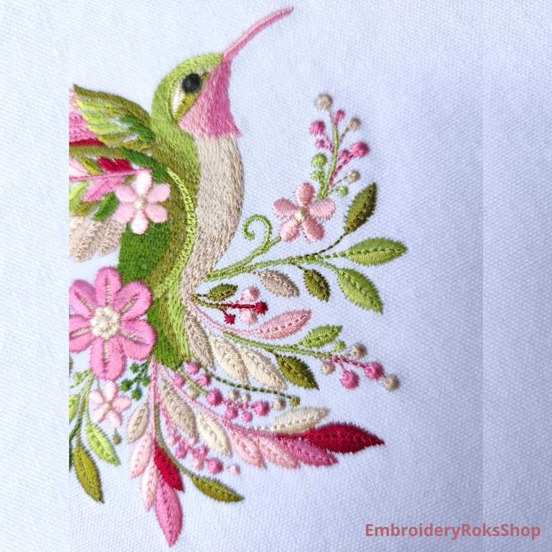 Floral hummingbird machine embroidery design with pink flowers, green leaves, cream feathers and botanical branches.