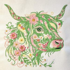 Può includere: Immagine ricamata di una testa di mucca delle Highlands, con intricati dettagli floreali verdi, rosa e gialli. Il design presenta un occhio verde chiaro, un naso rosa e corna curve, il tutto su uno sfondo bianco, con un tema botanico.
