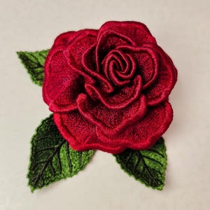 Red 3D FSL rose machine embroidery design with layered lace petals and green freestanding lace leaves.