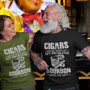 May include: Two people wearing t-shirts with the text "CIGARS SOLVE MOST OF MY PROBLEMS BOURBON DOES THE REST". The shirts are olive green and black. The graphic includes a cigar, a glass of bourbon, and stars.