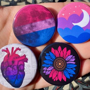 Pode incluir: Quatro broches de 1,25 polegadas com diferentes designs que representam a bandeira do orgulho bissexual. Os designs incluem um coração, um girassol, uma lua e nuvens, e uma galáxia.