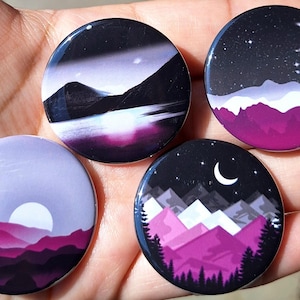 May include: Four round buttons with landscape designs. Each button features a different scene: a mountain range at sunset, a night sky with a crescent moon, and a mountain range with a full moon.