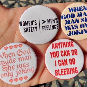 Pode incluir: Quatro botões redondos com texto. Um diz "WOMEN'S SAFETY > MEN'S FEELINGS." Outro diz "WHEN GOD MADE MAN SHE WAS ONLY JOKING!" O terceiro diz "When God made man She was only joking." O último botão diz "ANYTHING YOU CAN DO I CAN DO BLEEDING."