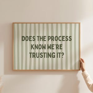 Op de afbeelding: Een rechthoekig ingelijst wandkunstwerk met een licht saliegroene achtergrond en verticale, handgetekende donkergroene strepen. De tekst "DOES THE PROCESS KNOW WE'RE TRUSTING IT?" is gedrukt in een vetgedrukt, donkergroen schreefloos lettertype.