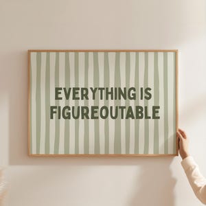 Könnte beinhalten: Gerahmter Druck mit dem Text "EVERYTHING IS FIGUREOUTABLE" in dunkelgrünen Buchstaben. Der Hintergrund zeigt vertikale Streifen in Hellgrün und Weiß. Der Rahmen besteht aus hellbraunem Holz.