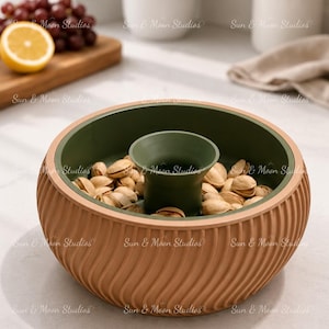 May include: A round, two-toned snack bowl featuring a textured, tan-colored exterior with vertical wavy ridges and a smooth, dark olive green interior. The bowl includes a central, elevated olive green cup designed for holding discarded shells.