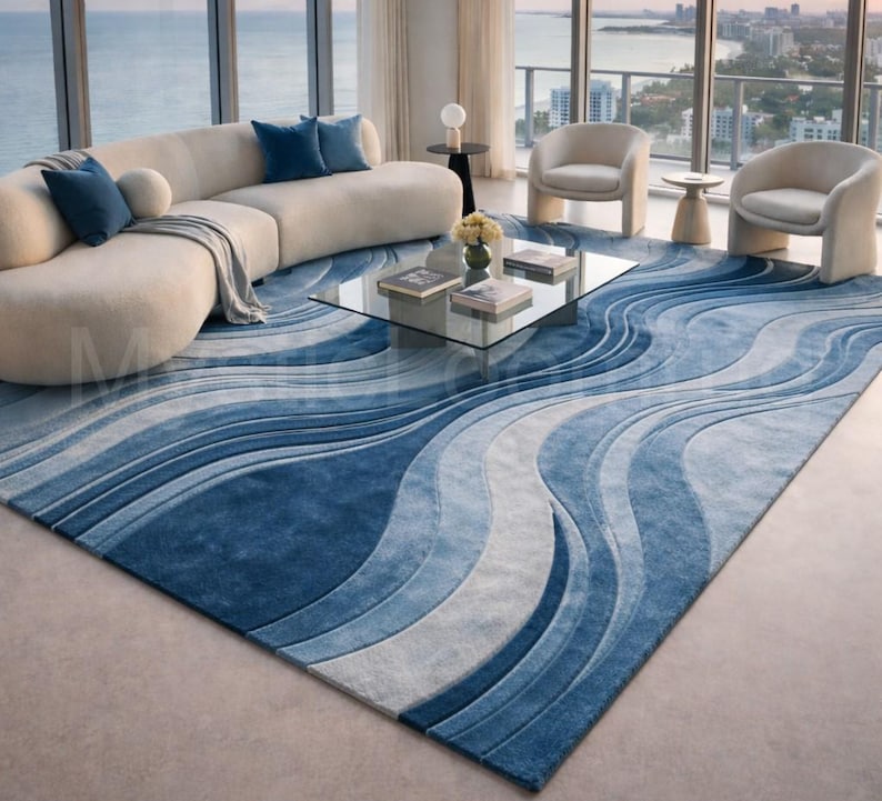 Modern blue abstract hand-tufted wool area rug with wave design placed in a luxury contemporary living room with sofa and glass table.