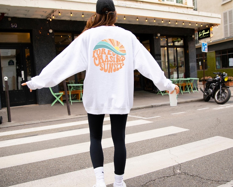 May include: White sweatshirt with a graphic of a sunset and the text "FOREVER CHASING SUNSETS".