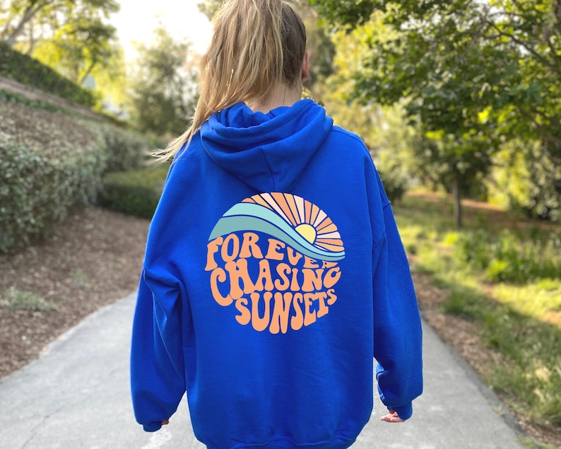 May include: A royal blue hoodie with a graphic of a sunset and waves on the back. The graphic says "FOREVER CHASING SUNSETS" in a retro font.