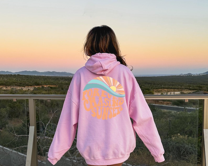 May include: Pink hoodie with a graphic of a sunset and waves with the text "Chasing Sunset".