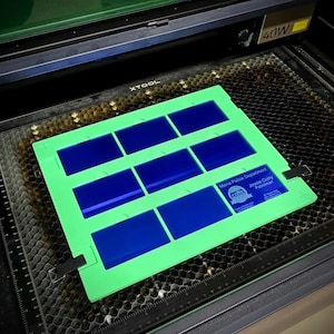 May include: A green sheet with nine blue rectangular spaces and a badge for the Mesa Police Department with the name Jessie Curry, Policeman. The sheet is on a black honeycomb surface.