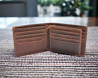 May include: A brown leather wallet with multiple card slots and a billfold. The wallet is open and lying on a patterned surface.