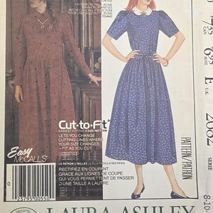 May include: A McCall's 2682 sewing pattern envelope for a Laura Ashley dress. The front shows two illustrations of the dress: one in brown with long sleeves and one in blue with short sleeves, a white collar, and a waist tie. Text includes "PETITE-ABLE" and "Cut-to-Fit".