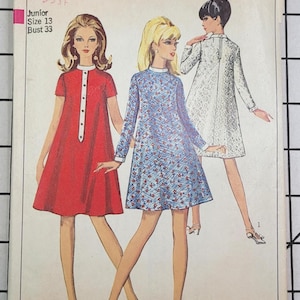 May include: Vintage Simplicity sewing pattern featuring three dress designs. The pattern includes a red dress with white trim, a blue floral dress, and a white lace dress. The pattern is for Junior size 13, with a bust size of 33 inches.