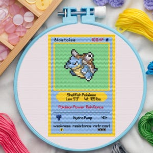 Könnte beinhalten: Kreuzstich-Stickerei einer Blastoise Pokémon-Karte. Das Design zeigt ein blaues und braunes, schildkrötenartiges Wesen auf grünem Hintergrund, mit Text wie "Blastoise" und "100HP". Die Karte ist 160 cm lang und wiegt 85,7 kg.