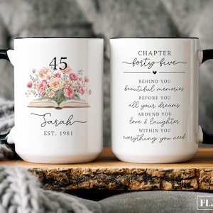 May include: White ceramic mug with a black handle and rim. One side features the number "45" above a floral arrangement and the name "Sarah". The other side reads "Chapter forty-five" with inspirational text.
