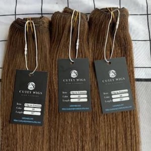 May include: Three bundles of brown hair extensions with tags. Each tag reads "CUTELY WIGS" and includes details like "Clip-in Extensions" and length measurements of 40.6, 45.7, and 55.9 cm. The hair is straight and a medium brown colour.