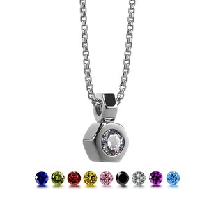 May include: A silver necklace with a hexagonal pendant featuring a clear round gemstone. The pendant is attached to a silver chain. The image also shows a variety of colored gemstones in a row below the necklace.