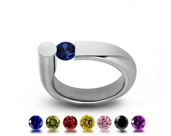 PORTANTE Flat and rounded tubular bypass ring with off centered tension set Blue Sapphire in stainless steel