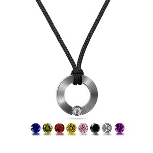 May include: A silver ring pendant necklace with a black cord. The pendant has a small clear gemstone in the centre. The necklace is available with a variety of coloured gemstones, including blue, green, yellow, red, pink, black, white, and purple.