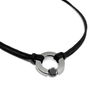 May include: A black cord necklace with a silver-coloured circular pendant and a black gemstone. The cord is knotted on either side of the pendant. The background is white.
