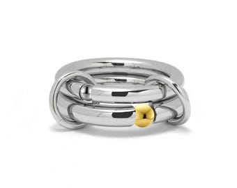 PLUTO connected interlocked  tubular rings with tension set gold sphere in stainless steel