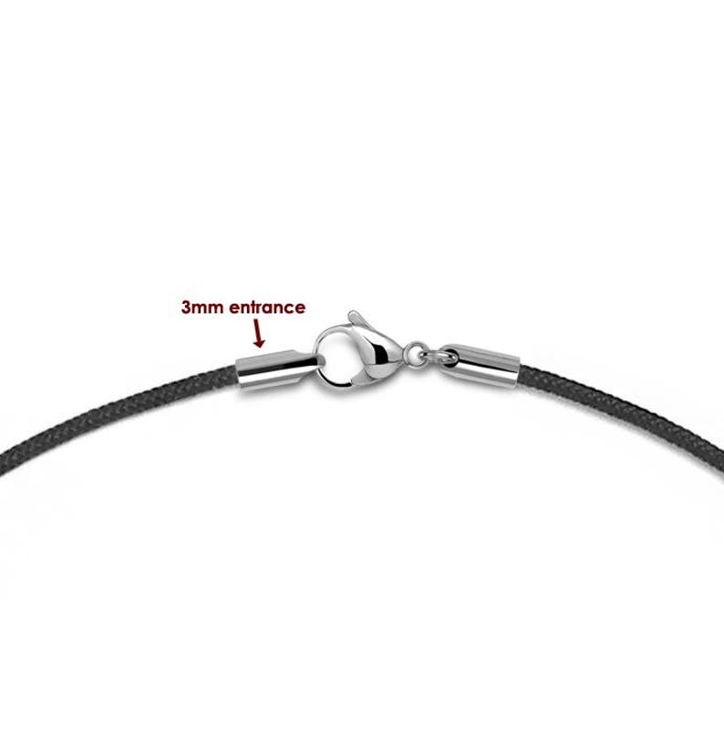 May include: A black cord necklace with a silver clasp. The clasp has a 3mm entrance, as indicated by the text "3mm entrance".