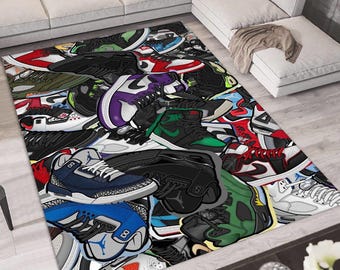 May include: A rectangular rug featuring a vibrant collage of colorful sneakers. The design includes various shoe styles in shades of blue, green, red, black, and purple. The rug is placed on a light-colored wooden floor, with a white sofa in the background.