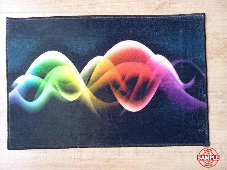 May include: A rectangular rug with a dark blue background and a vibrant, colorful design. The design features flowing, abstract shapes in shades of green, yellow, orange, pink, and purple. The rug has a black border and a "SAMPLE" stamp.