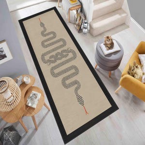 Peut inclure: Un tapis de couloir beige avec un motif de serpent noir et blanc et une bordure noire. Le tapis est posé sur un sol en bois avec une chaise jaune et un tabouret gris en arrière-plan.