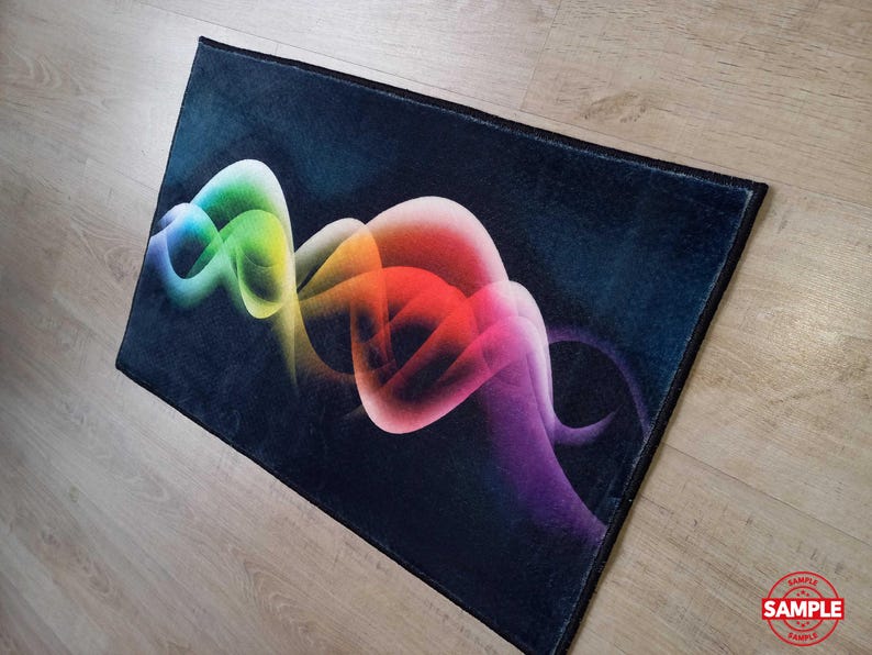 May include: A rectangular rug with a dark blue background and a vibrant, abstract design. The design features flowing, colorful shapes in shades of green, yellow, orange, red, pink, and purple. The rug has a black border and is placed on a wooden floor.