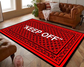 Puede incluir: Alfombra roja y negra con la inscripción "KEEP OFF" en blanco en una fuente decorativa. La alfombra tiene un patrón geométrico.