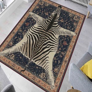 Puede incluir: Una alfombra azul y beige con un diseño de estampado de cebra. La alfombra tiene un borde detallado con patrones florales en tonos rojos, naranjas y amarillos.