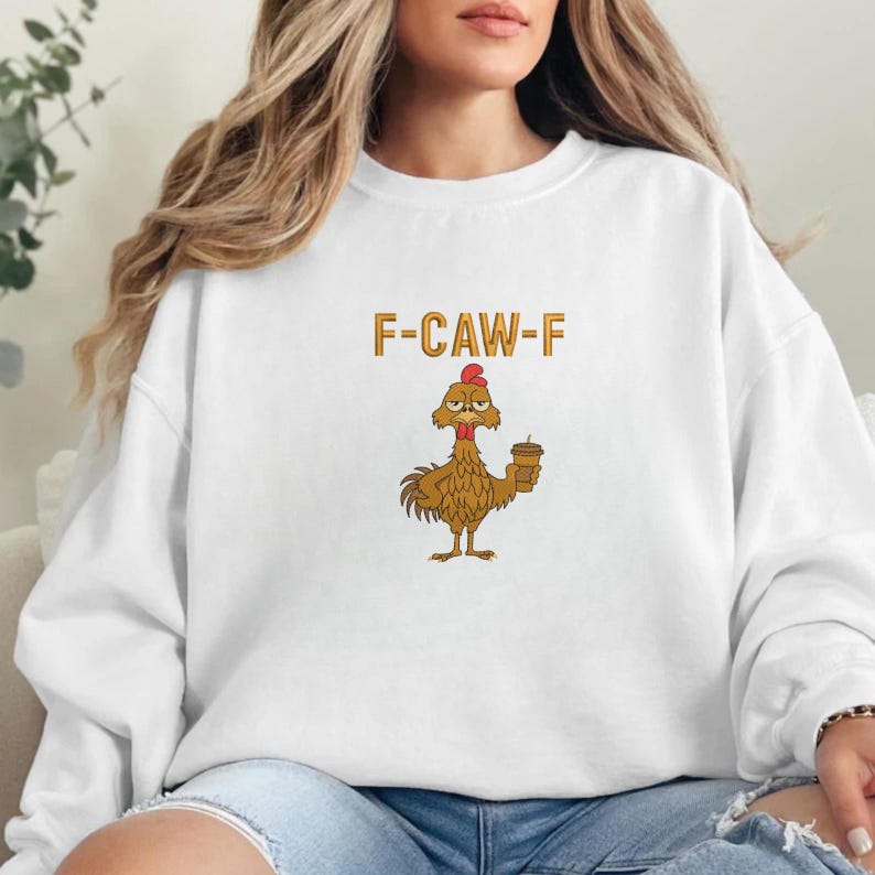 K&ouml;nnte beinhalten: Wei&szlig;es Sweatshirt mit dem Text "F-CAW-F" in orangefarbenen Buchstaben. Darunter befindet sich ein Cartoon-Huhn mit rotem Kamm, das eine Kaffeetasse h&auml;lt. Das Huhn ist braun und hat einen w&uuml;tenden Gesichtsausdruck.