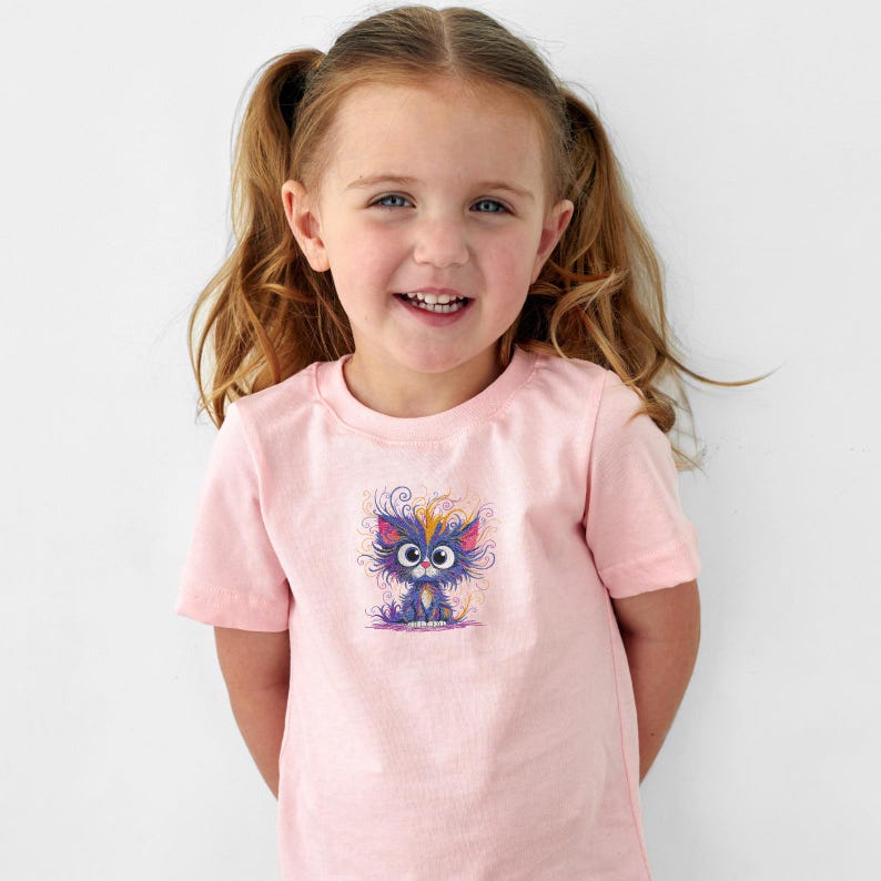 以下が含まれることがあります： カラフルな漫画の猫のデザインが施された、明るいピンク色のTシャツ。猫は青、紫、黄色、オレンジ色のアクセントがあります。Tシャツは幼い子供が着ています。