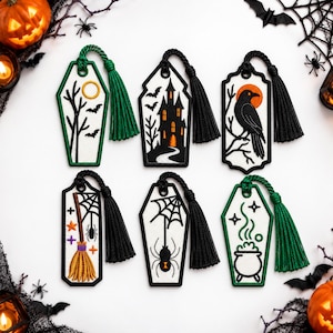 May include: Six embroidered bookmarks with Halloween motifs including a coffin with a moon and bats, a haunted house, a crow, a broomstick with a spider web, a spider, and a cauldron, each featuring a decorative tassel in green or black.