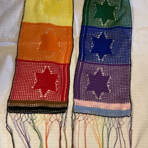 May include: A rainbow crocheted tallit with a Star of David in each color panel. The tallit has a black border and rainbow fringe.
