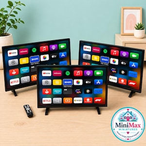 May include: Three miniature black television screens displaying a colorful grid of app icons including Netflix, YouTube, and Zoom, accompanied by a small black remote control. The screens are arranged on a light wood surface with thin black stands.