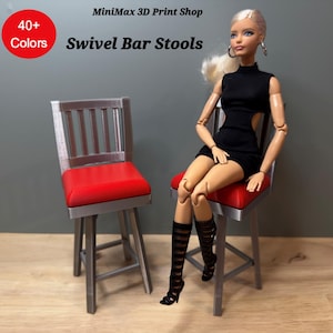 May include: Two miniature swivel bar stools with red seats and silver frames. The stools have a backrest with vertical slats. The image includes the text "40+ Colors" and "Swivel Bar Stools" from the "MiniMax 3D Print Shop". A doll is sitting on one of the stools.
