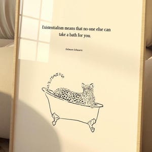 May include: A framed print on a cream background featuring a black line drawing of a leopard sitting in a clawfoot bathtub. The text reads: Existentialism means that no one else can take a bath for you. Delmore Schwartz is printed below the quote.