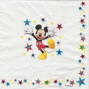 May include: White paper napkin with a cartoon image of Mickey Mouse in red shorts and yellow shoes. Mickey Mouse is surrounded by yellow, blue, and red stars. The text "© Disney" is in the bottom right corner.