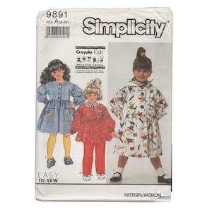 Peut inclure: Une pochette de patron de couture Simplicity, numéro 9891, taille A (2-6X), présentant des motifs Crayola Kids Favorite Colors. La couverture affiche des illustrations de trois tenues : une robe bleue, un haut rouge avec pantalon et une robe blanche imprimée.