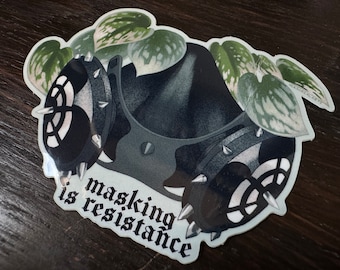 May include: A black and white sticker with a gas mask and leafy plants. The text "masking is resistance" is written in a gothic font.
