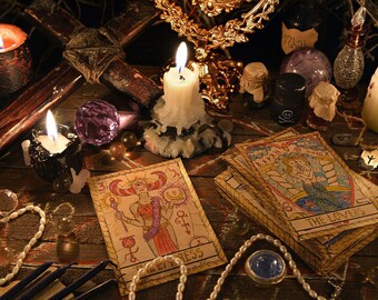 May include: A tarot card reading set up with candles, crystals, and tarot cards. The cards are spread out on a wooden table and include the cards "The Empress" and "The Lovers".