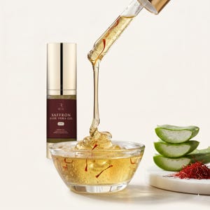 May include: A clear glass bowl filled with a golden liquid, saffron threads, and a dropper dispensing more liquid. A bottle labeled "Saffron Aloe Vera Gel" and sliced aloe vera are also present. The image highlights skincare products.